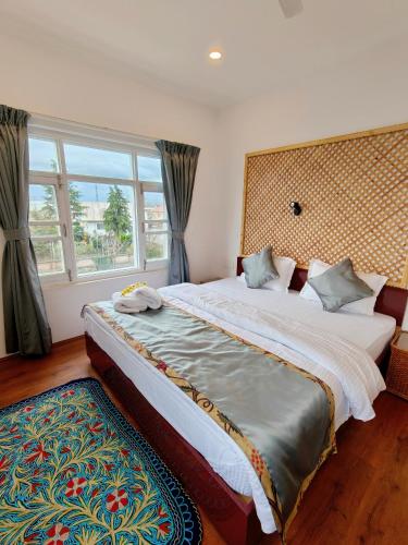 a bedroom with two beds and a large window at Maskan by Rafiqi Estates - Deluxe 2BHK & Studio Apartments in Srinagar
