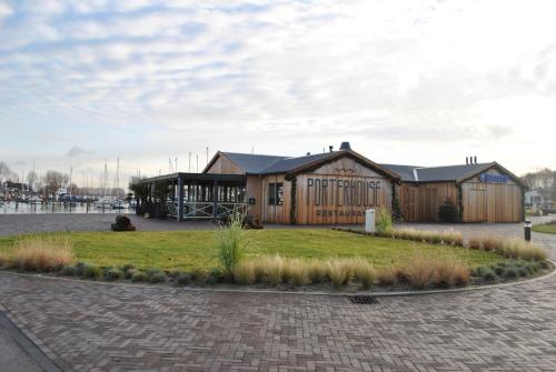 un gran edificio de madera con una zona de césped delante de él en Marinaparcs Naarden en Naarden