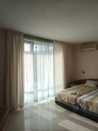 a bedroom with a bed and a large window at Къща за Гости ,,Afrikana,, in Sveti Vlas