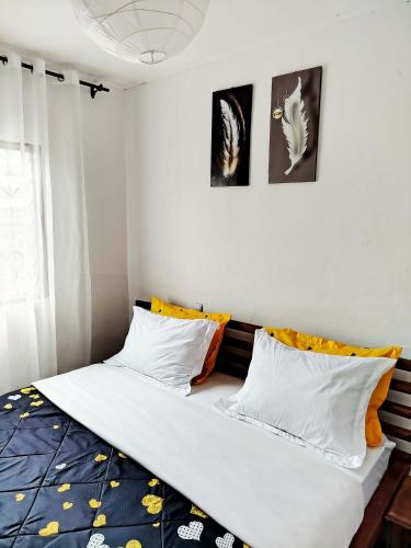 a bedroom with a bed with white and orange pillows at Côté Plage Kribi Studio Soleil in Kribi
