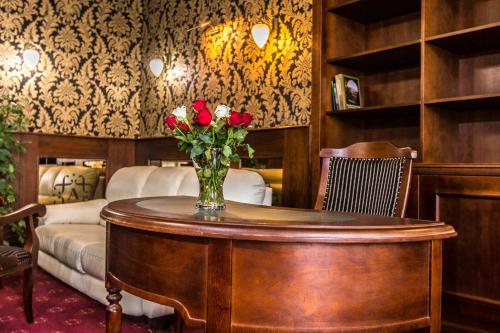 a vase of roses on a table in a room at Boutique Hotel Annuska in Balatonfüred