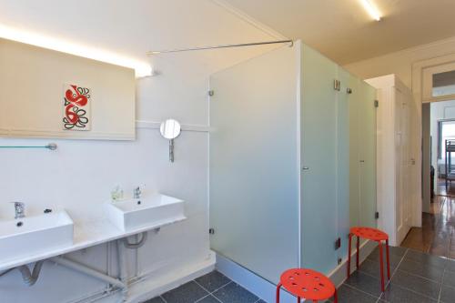 a bathroom with two sinks and a red stool at Hostel Alegria in Porto