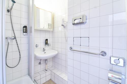 ein weißes Bad mit einem Waschbecken und einer Dusche in der Unterkunft Hotel Europa City in Berlin