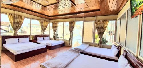 a room with two beds and windows in a building at Thanh Thao Dalat Hotel in Da Lat