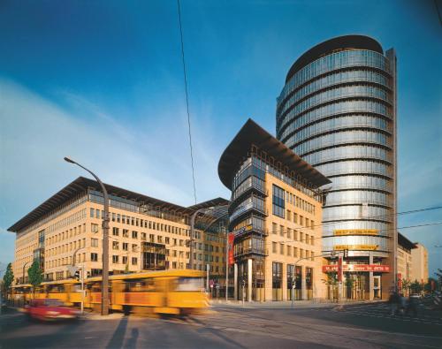 a yellow bus driving past a tall building at Hotel Elbflorenz Dresden in Dresden