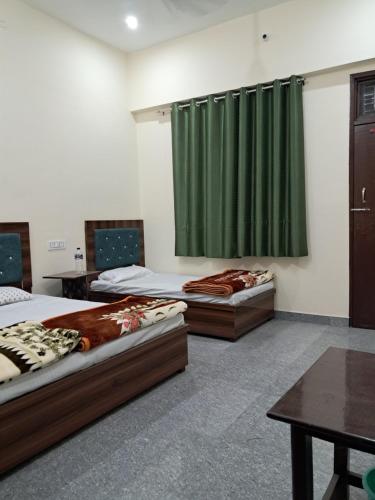 two beds in a room with a green curtain at Krishna palace in Pīpalkoti