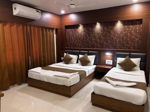 a bedroom with two beds and a wall at Hotel Volga Plaza in Mumbai