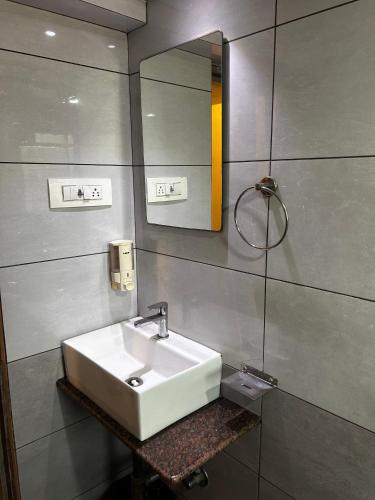 a bathroom with a white sink and a mirror at Hotel Volga Plaza in Mumbai