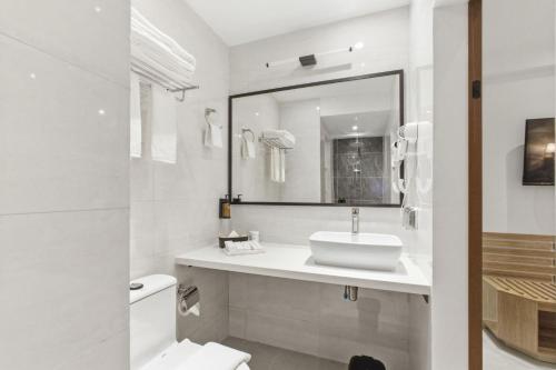 a white bathroom with a sink and a mirror at Hotel Amber Seaside in Hulhumale