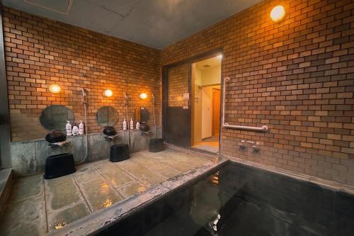 a bathroom with a large tub in a brick wall at アリビオ伊豆 in Ito