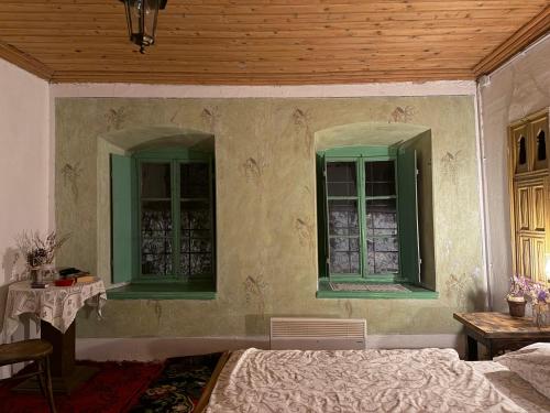 a bedroom with green windows and a bed and a table at National monument Mehmedbasica Kuca in Stolac