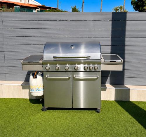 a grill sitting on the grass next to a fence at Suite Coco in Maspalomas