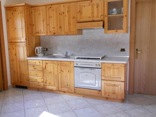uma cozinha com armários de madeira e um forno de fogão branco em Bait da Giusy em Livigno