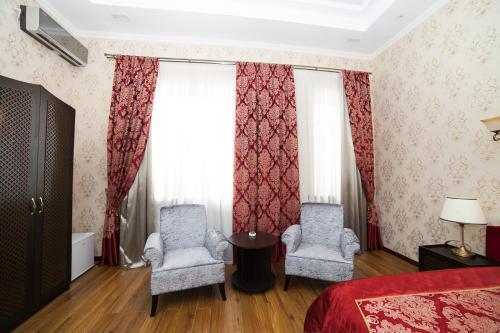 a bedroom with two chairs and a bed and curtains at Park Hotel in Karagandy