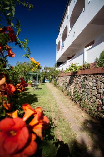 a stone wall next to a building with red flowers at Grand Hotel De Rose in Scalea