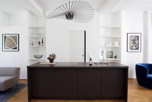 a kitchen with a black island in a living room at August The Boardinghouse in Hamburg