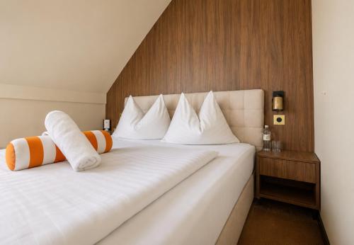 a bedroom with a white bed with orange and white pillows at Motel Reich in Velenje
