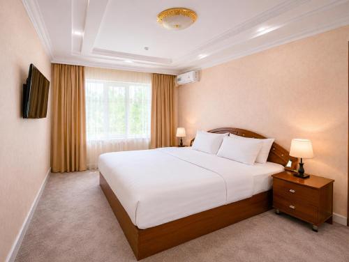 a bedroom with a large white bed and a window at Asson Hotel Termez in Termiz
