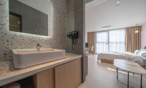 a bathroom with a sink and a bedroom with a bed at Brown Dot Hotel Siheung Geobukseom in Siheung