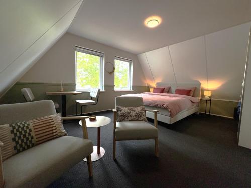 a bedroom with a bed and a chair and a table at B&B Wetterwille in Opeinde