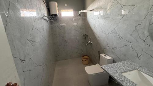 a bathroom with a white toilet and a marble wall at S&J Hotel & Banquet in Bhabua
