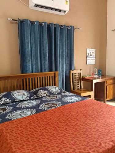 a bedroom with a bed with a blue curtain and a desk at Devaki Tourist Home in Ambalapulai