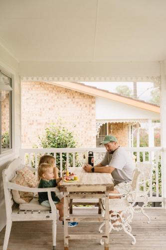 a man and a little girl sitting at a table on a porch at Lady Rose Cottage Jamberoo in Jamberoo