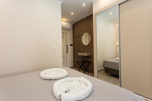 a bedroom with two white beds and a mirror at Corfelia Seaview Suites in Ipsos