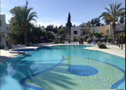 ein großer blauer Pool mit Palmen und Gebäuden in der Unterkunft Paphos Studios in Paphos City