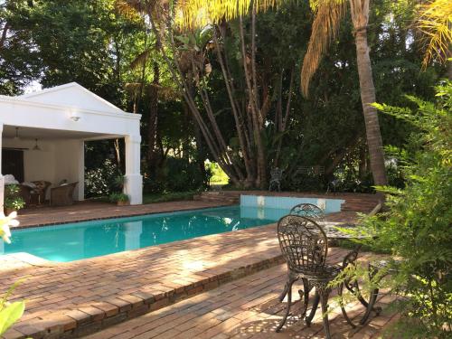 a swimming pool with two chairs and a table next to it at Polokwane Place in Polokwane
