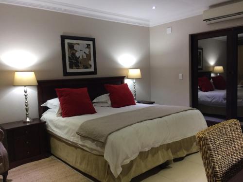 a bedroom with a large bed with red pillows at Polokwane Place in Polokwane