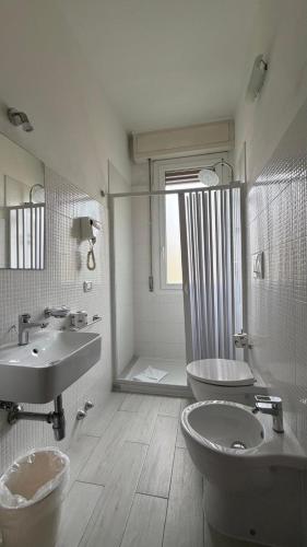 a bathroom with two sinks and a toilet and a shower at Hotel Primula in Lido di Savio