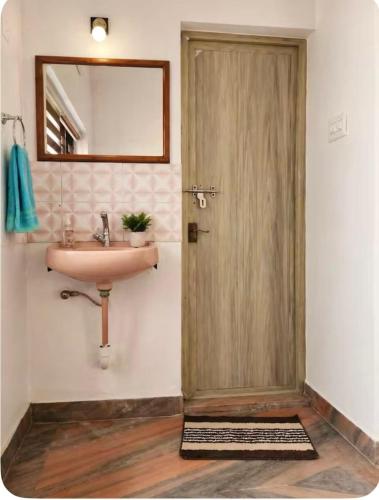 a bathroom with a sink and a door with a mirror at Kandass Homestay in Trichūr