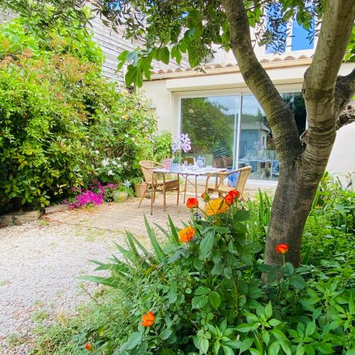 a table and chairs in a garden with flowers at La Maison aux coquillages in Portel-des-Corbières