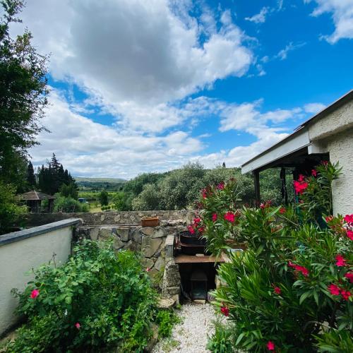 a garden with pink flowers and a stone wall at La Maison aux coquillages in Portel-des-Corbières