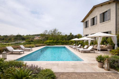 a swimming pool with chairs and umbrellas next to a house at Capalbio - Retreat in Capalbio