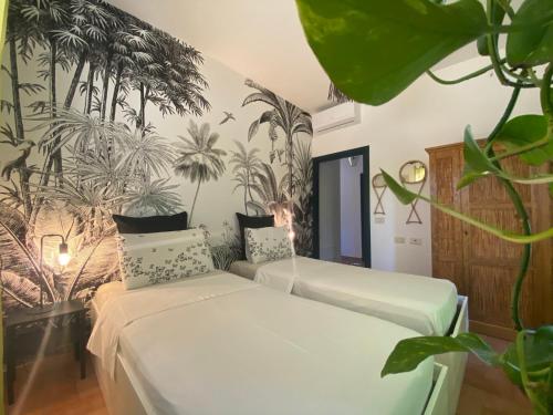 two beds in a room with palm trees on the wall at Casa Jasmine by Lisetta in Migiana