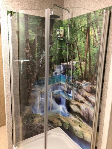 a shower with a painting of a waterfall at Pension Erlerhof Chez Karin in Tulfes