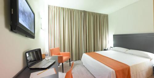 a hotel room with a bed and a laptop on a desk at Hotel H2 Avila in Ávila