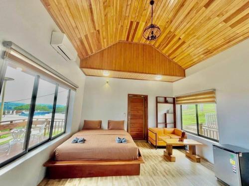 a bedroom with a bed and a large window at Highland Park Mondulkiri in Phumĭ Pu Klé (2)