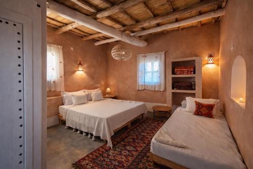a bedroom with two beds and a couch at Tigmi Hamid Découverte des traditions et de la culture berbère in Aït Benhaddou