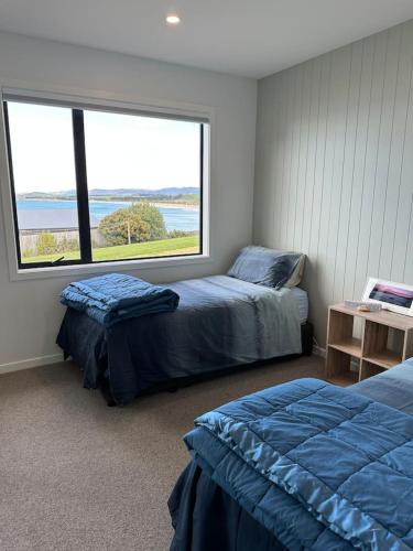a bedroom with two beds and a large window at Coastal Luxe Villa in Kakanui