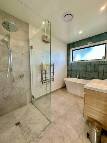 a bathroom with a shower and a tub and a sink at Coastal Luxe Villa in Kakanui