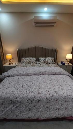 a bedroom with a large bed with two lamps on tables at 2 BHK Starry Night Penthouse in Islamabad