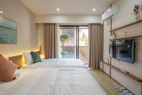 a bedroom with a large white bed and a tv at MIRO Homestay in Hue