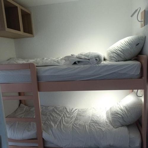 a bunk bed with white sheets and pillows on it at Appartement Vignec proche Saint-Lary in Vignec