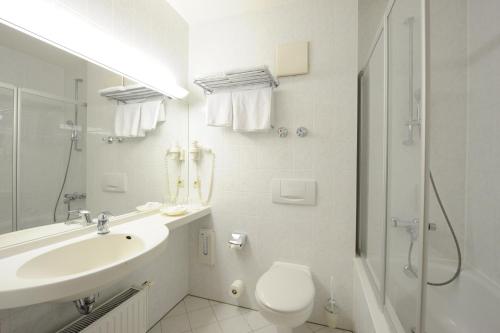 a white bathroom with a sink and a toilet at Hotel Poinger Hof in Poing