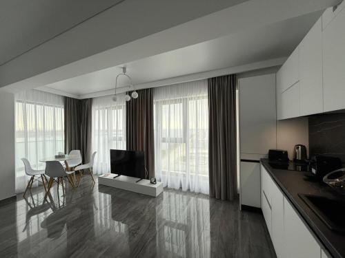 a kitchen and living room with a television and a table at Seaside Escape - Luxury Apartment in Năvodari