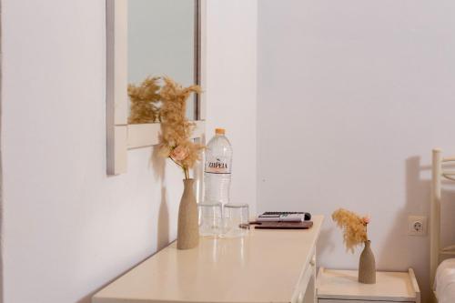 a table with a bottle of water and two vases with flowers at Wilde Rose Hotel in Dassia
