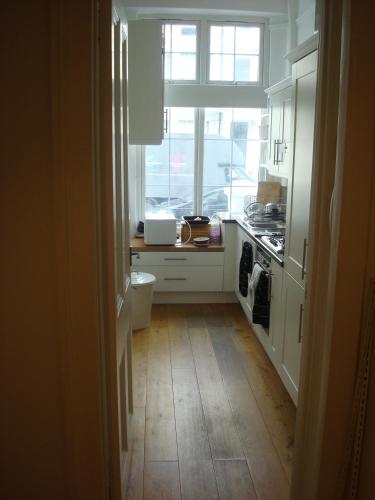 a kitchen with a window and a wooden floor at Exceptional guest rated 1 bedroom Kensington apartment with Super Wifi in London